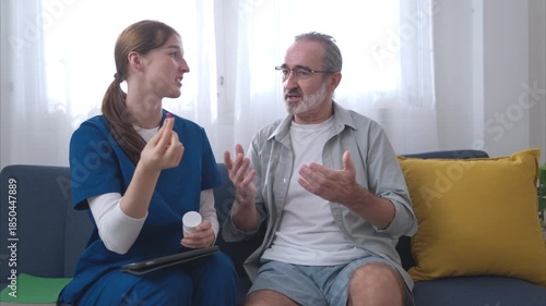 A female nurse assists an elderly patient in couch of living room with explain medication