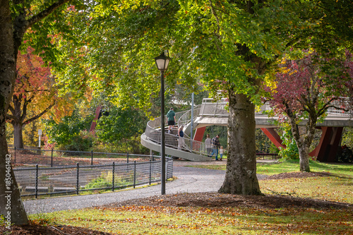 Several people on the ramp to a footbridge in a city park in fall