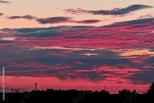 Dramatic sunset sky filled with pink and purple clouds over a dark horizon, capturing a vibrant and atmospheric evening scene.