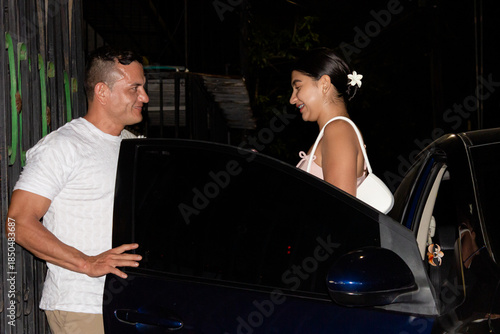 A young man is opening a car door for a beautiful young woman for her birthday party at an evening event in Neiva, Huila, Colombia. Concept of love and happiness