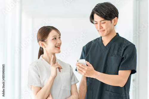 Billede på lærred Medical workers in scrubs smiling and talking with smartphones, medical staff, m
