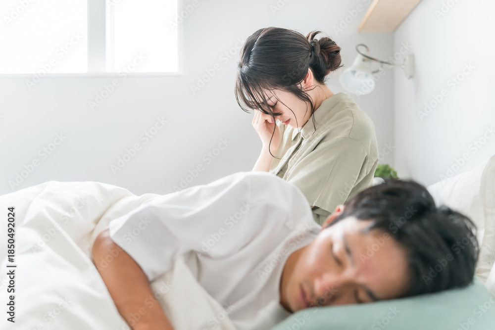 Obraz premium A woman suffering from sleep deprivation and a man sleeping in bed