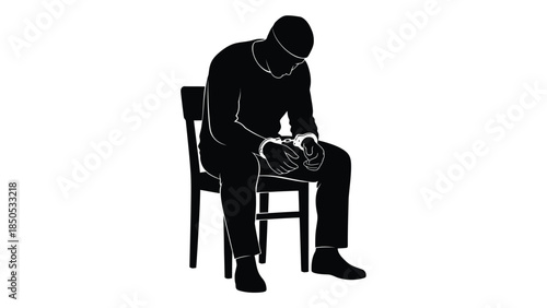 Silhouette of a man in handcuffs seated alone looking down in despair against a white background