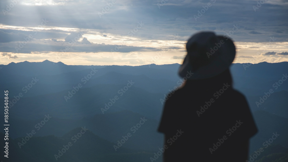 Fototapeta premium Blurred rear view of a woman watching sunset sky on the mountain peak