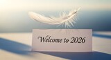 A feather hovers above a welcome to 2026 card on a surface