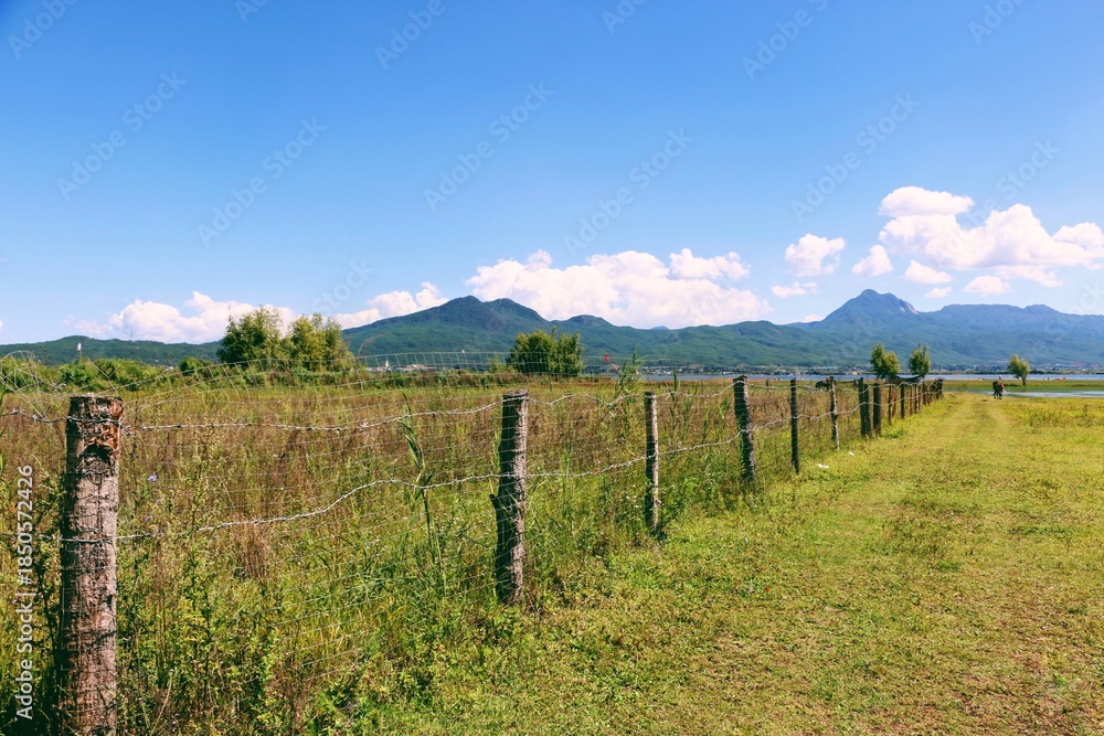 Naklejka premium Blue Sky White Clouds Meadow Fence Landscape