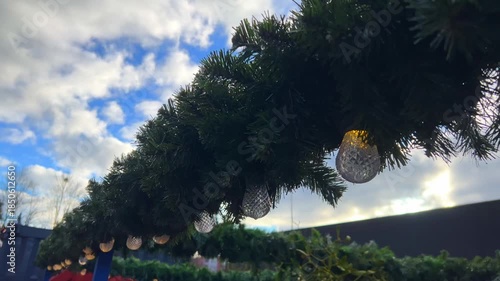Bright lights hang from greenery in a bustling outdoor area. Christmas market in Gdansk, Poland