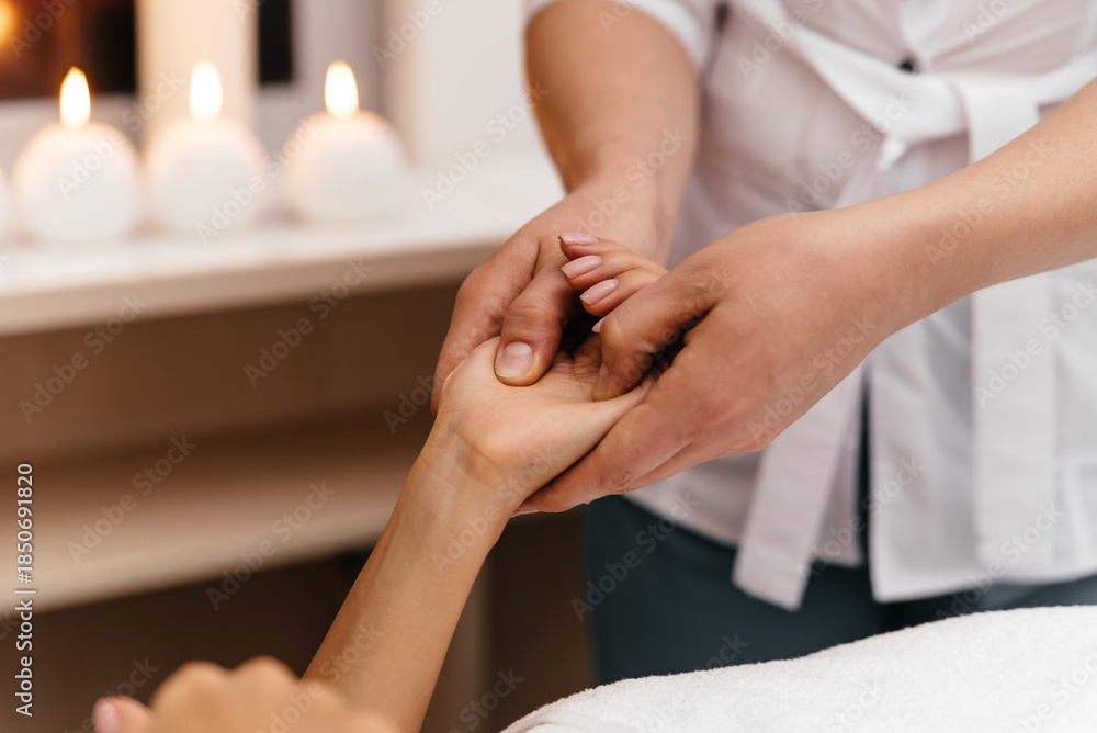 Obraz premium Hand massage. Female therapist pressing specific spots on black lady palm. Professional health and wellness acupressure manipulations, closeup
