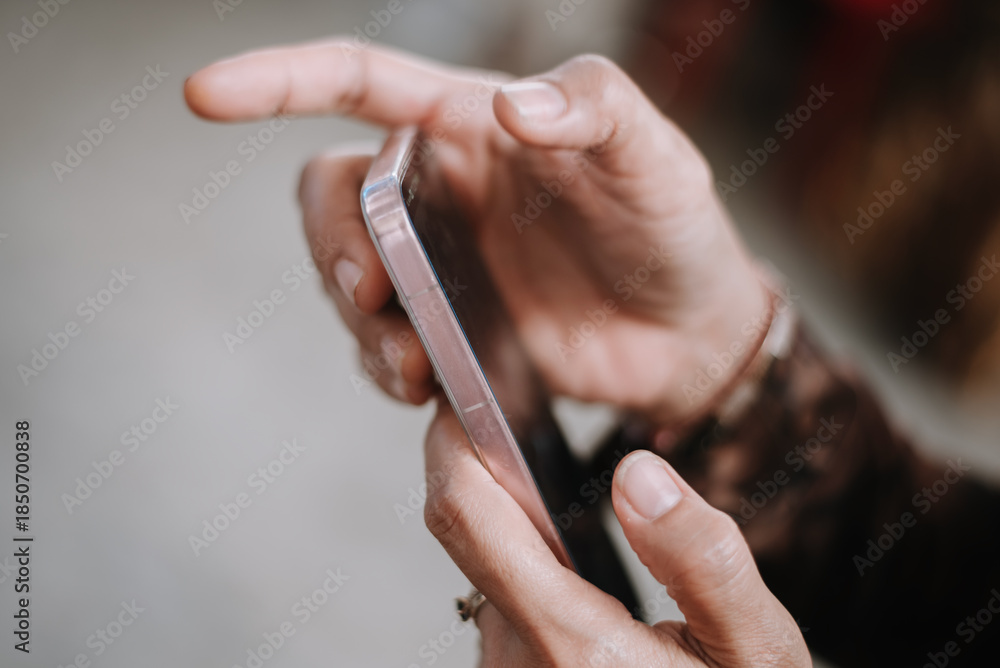 Obraz premium Close-Up Of Hands Holding A Pink Smartphone With Focused Gesture
