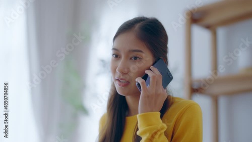Young asian woman talking mobile smartphone while sitting on couch at house. Upset asian woman frustrated by problem with work or relationships, feeling despair and anxiety