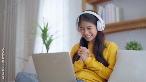 Funny euphoric young asian woman celebrating winning or getting ecommerce shopping offer on computer laptop. Excited happy girl winner looking at notebook celebrating success