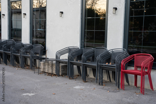 Metal chairs stacked in front of a currently closed restaurant. Neatly arranged seating equipment in an urban outdoor setting.


