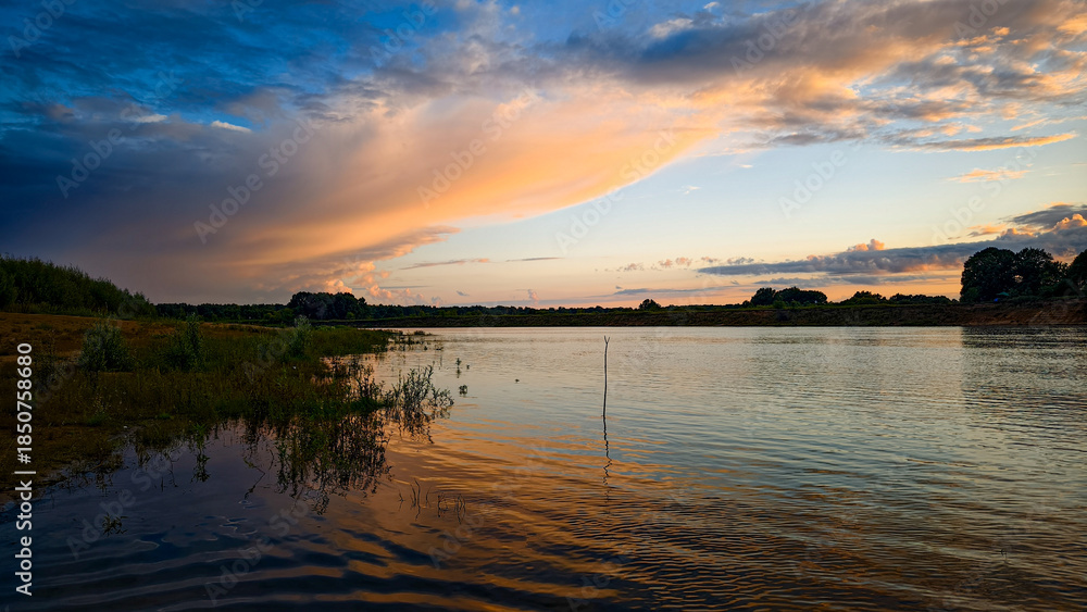 Naklejka premium Sunset on the cloudy river.