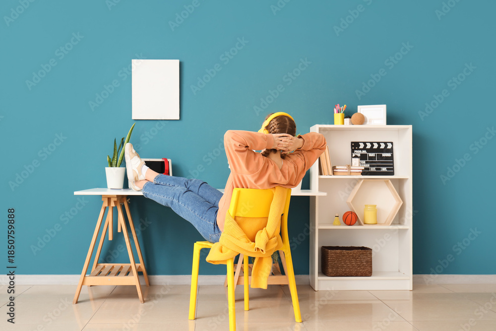 © Pixel-Shot - Teenage girl with headphones resting at table in room, back view © Pixel-Shot - Teenage girl with headphones resting at table in room, back view