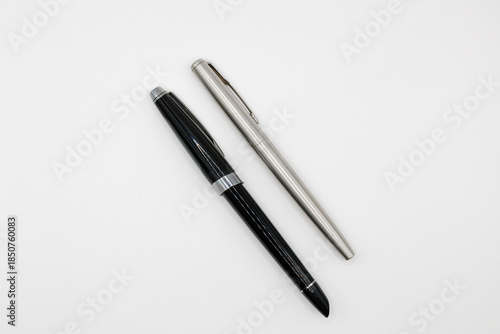 Minimalist studio shot of two fountain pens, one black and one silver, isolated on a white background. Concept of writing, education, business, stationery, and classic elegance.