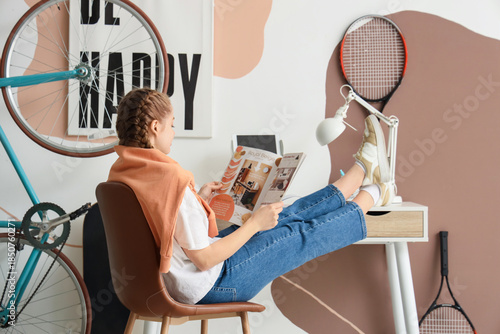 Teenage girl reading magazi...