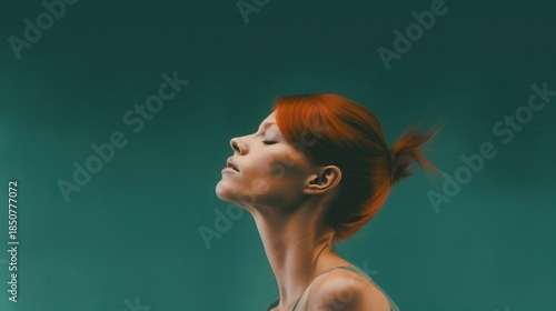 A serene woman with red hair gazes upwards, capturing a moment of tranquility against a green backdrop.