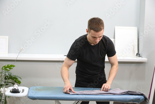 Young man ironing his clothes at home