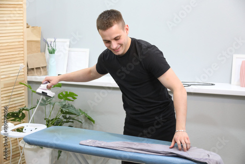 Young man ironing his clothes at home