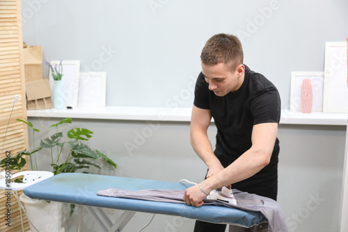 Young man ironing his clothes at home