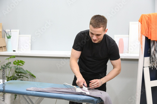 Young man ironing his clothes at home