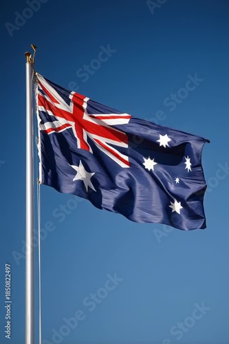Australian flag waving in the wind against a clear blue sky, showcasing vibrant colors and distinct patterns, capturing the dynamic movement of fabric in motion