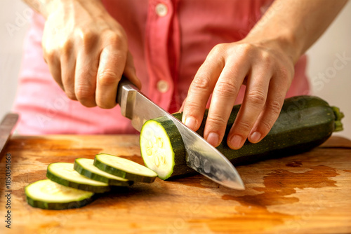 Wallpaper Mural Close-Up of Hands Slicing Fresh Zucchini on Wooden Cutting Board for Healthy Home Cooking Torontodigital.ca