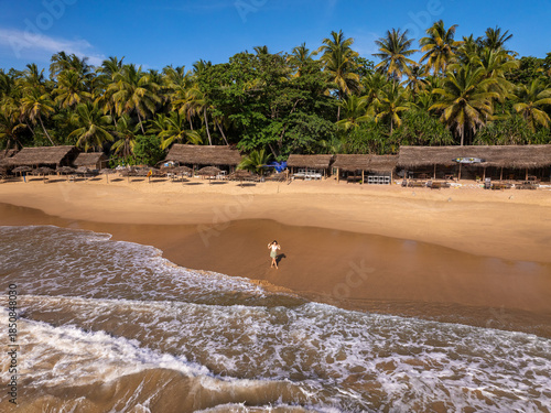 Young Woman Walking on Golden Sand Beach with Thatched Beach Huts, Goyambokka Beach, Sri Lanka