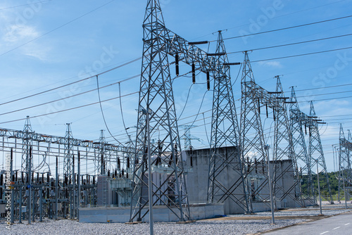 High voltage electric substation with power transmission lines and steel towers under blue sky. Electrical infrastructure for energy distribution, power supply industry and engineering technology.
