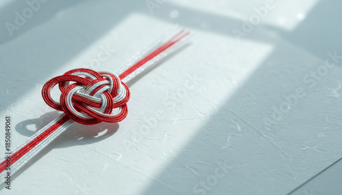 白い背景に置かれた紅白の水引による梅結びの伝統的な正月飾りのクローズアップ