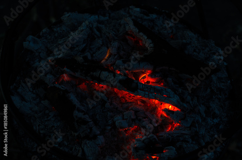 Glowing Embers in Cold Night Ashes Create Warm Light and Subtle Fire Spots in a Fire Pit