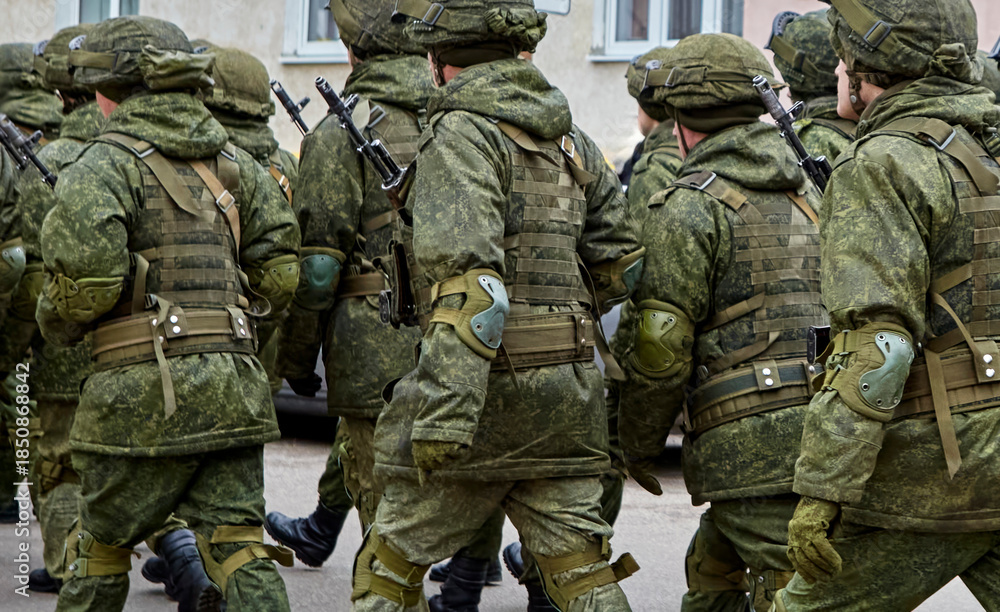 Fototapeta premium Soldiers in military uniforms marching through urban area during daylight hours in a routine exercise
