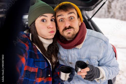 Couple having fun taking selfies while taking a winter vacation road trip break
