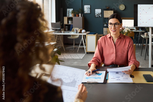 Fotografie Caucasian young woman wearing glasses conducting business meeting with colleague