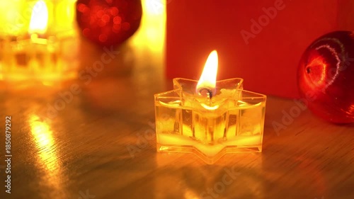 Red gift box and candlelight on a wooden table.