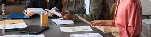 Wallpaper Mural Diverse group of professionals collaborating at table, reviewing business documents and analyzing printed charts, hands of Caucasian women and Black man visible, header Torontodigital.ca