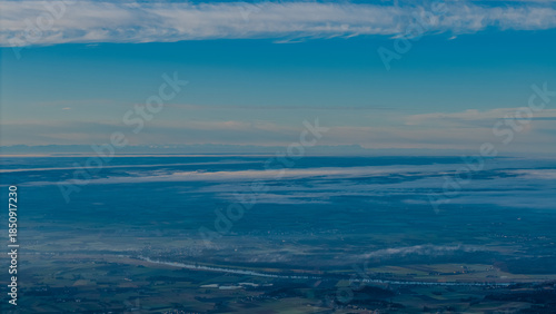 Weite Aussicht auf die Landschaft von oben bei klarem Himmel und Wolken am frühen Morgen