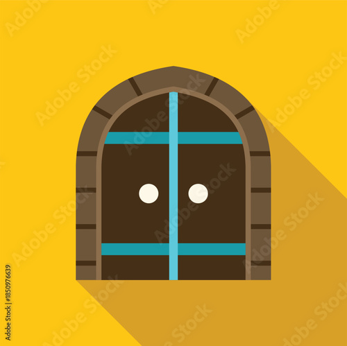 Brown arched medieval wooden door with turquoise metal bands on a yellow wall creating a long shadow