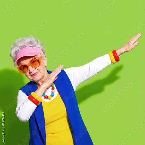 Elderly woman dances against bright green background in summer outfit
