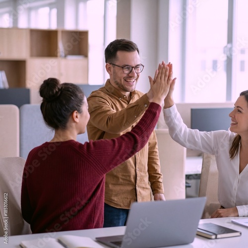 Team members celebrate success with high-fives in office setting
