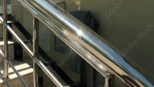 Shiny metallic handrail with bright reflections in a modern building interior.