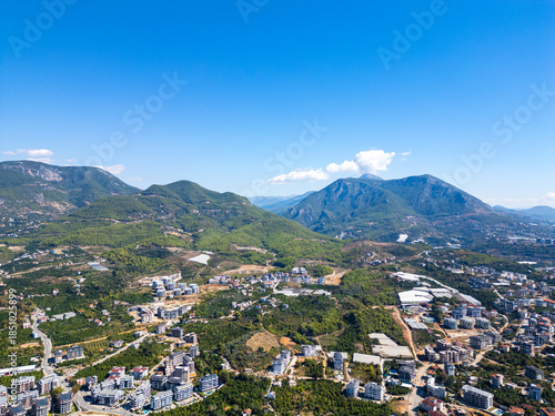 Scenic Drone Shot of a Mediterranean Mountain Pass, Revealing a Mix of Urban Development, Farmland, and Dense Forest on a Cloudy Day
