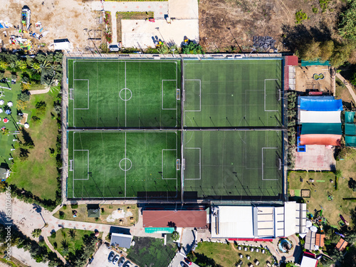 High-Angle Drone View of Four Adjacent Green Artificial Turf Soccer Fields in a Sports Complex