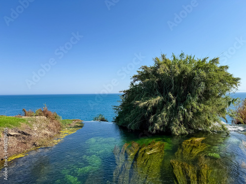 Upper Duden Waterfalls in Antalya, Turkey, Showing the Waterfall's Edge and Lush Greenery Against the Deep Blue Mediterranean Sea