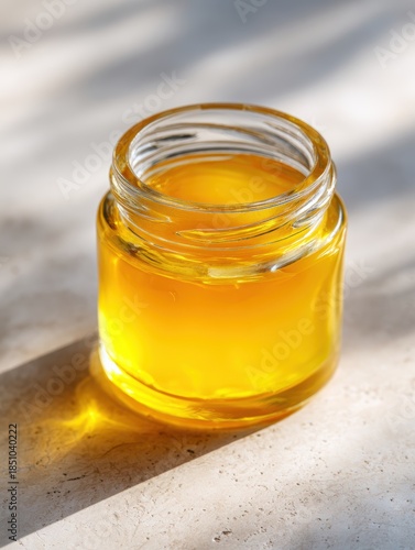 Glass Jar Filled with Golden Honey on Light Textured Surface Natural Sunlight