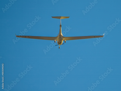 Glider-like plane flying in the blue sky
