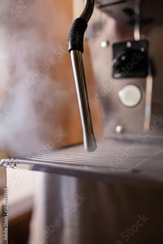 Minimal close-up of a steam wand on a professional espresso machine. Rising steam, warm light and metallic textures create a clean, industrial coffee aesthetic