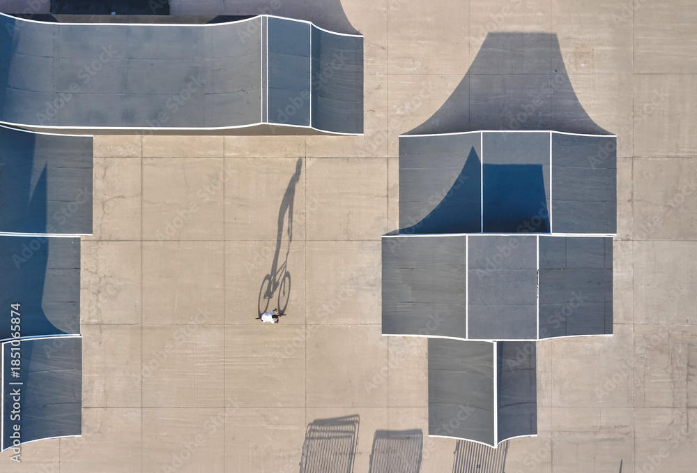Fototapeta premium Biker performing tricks in a urban skatepark with ramps and shadows