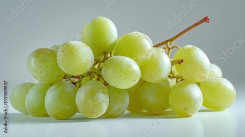 A bright and fresh shot of white-backed grapes, arranged carefully on a white surface, their light green color and smooth texture shining under soft lighting