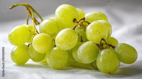 A bright and fresh shot of white-backed grapes, arranged carefully on a white surface, their light green color and smooth texture shining under soft lighting